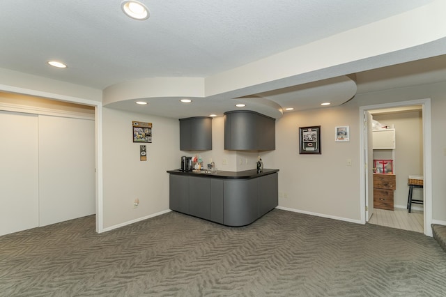 kitchen with gray cabinetry, sink, and dark carpet