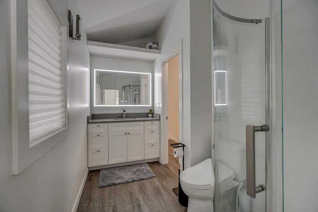 bathroom with vanity, toilet, wood-type flooring, and vaulted ceiling