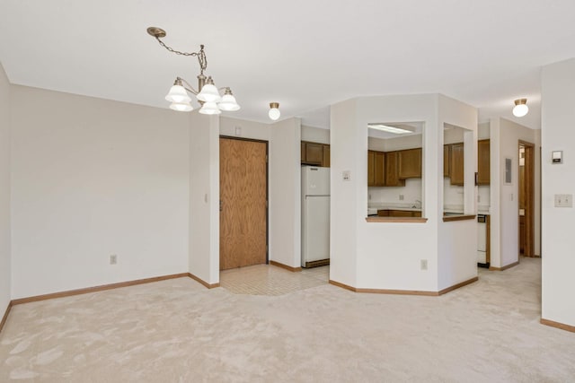 interior space featuring white refrigerator, light colored carpet, an inviting chandelier, and hanging light fixtures