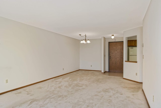 carpeted spare room with an inviting chandelier