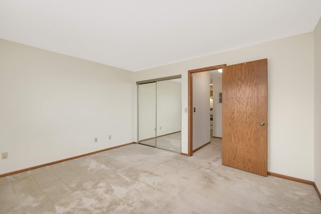 unfurnished bedroom with light colored carpet and a closet