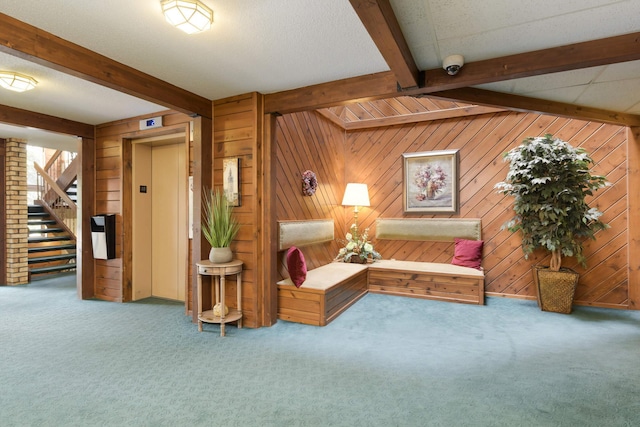 carpeted living room with beamed ceiling, elevator, and wooden walls