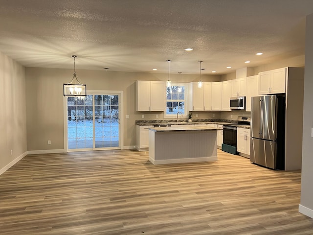 kitchen featuring white cabinetry, stainless steel appliances, light hardwood / wood-style flooring, and pendant lighting