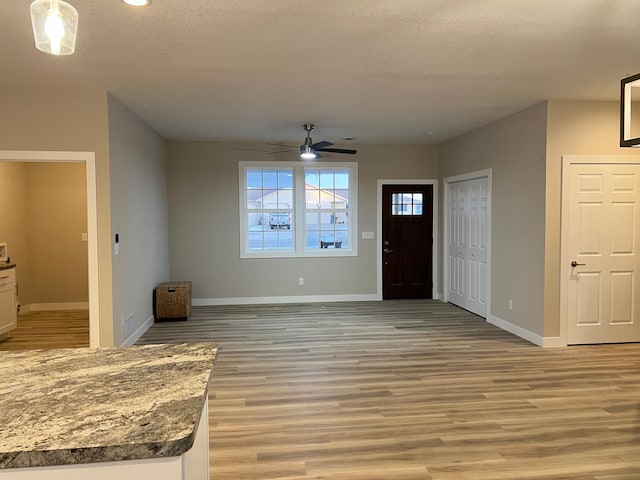 foyer with ceiling fan, light hardwood / wood-style floors, and a textured ceiling