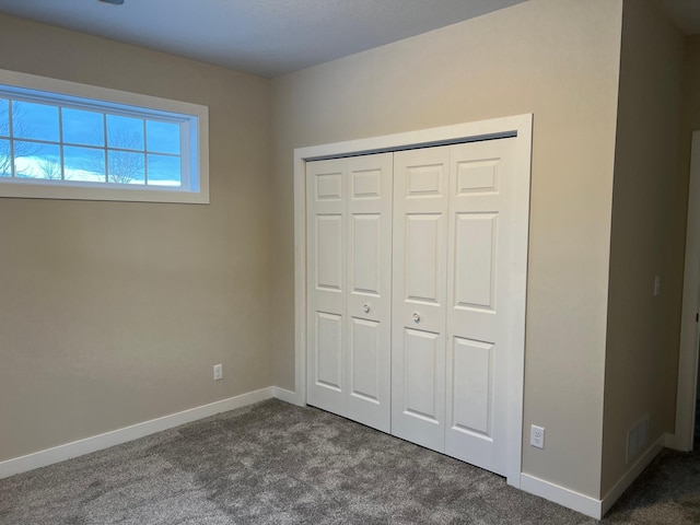 unfurnished bedroom with dark colored carpet and a closet