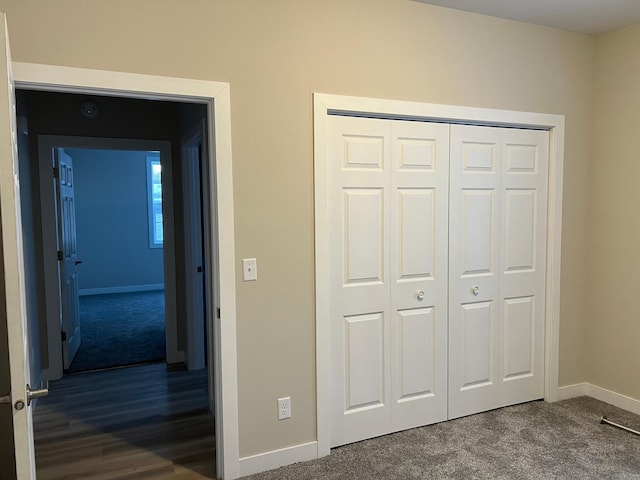 unfurnished bedroom with dark carpet and a closet