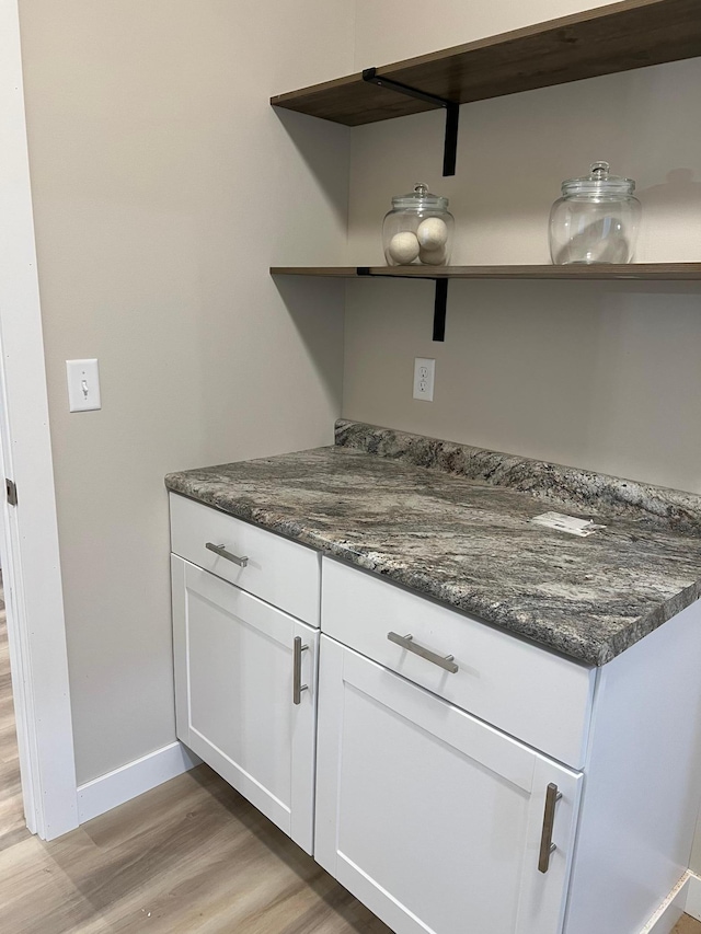 kitchen featuring white cabinetry, light hardwood / wood-style floors, and dark stone counters