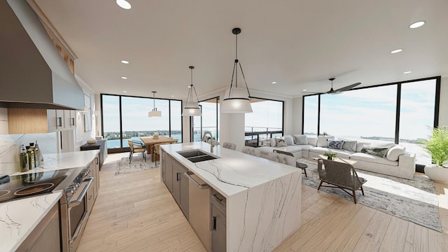 kitchen featuring hanging light fixtures, sink, light wood-type flooring, appliances with stainless steel finishes, and light stone counters