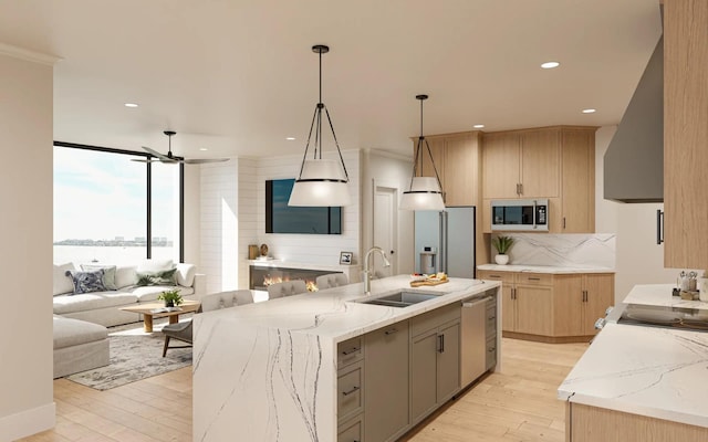 kitchen with light stone counters, a spacious island, sink, light hardwood / wood-style floors, and stainless steel appliances