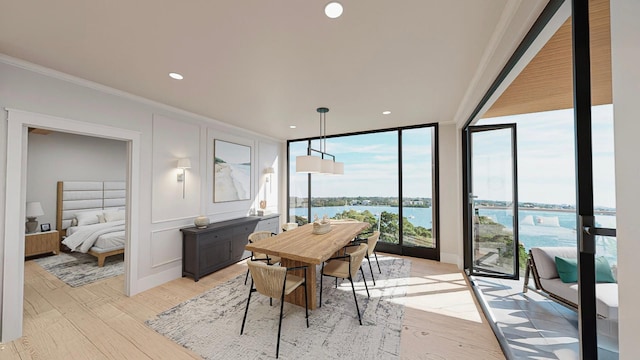 dining space featuring ornamental molding, light hardwood / wood-style flooring, a water view, and floor to ceiling windows