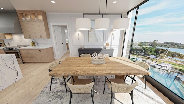 dining space with light hardwood / wood-style floors, ornamental molding, and a water view