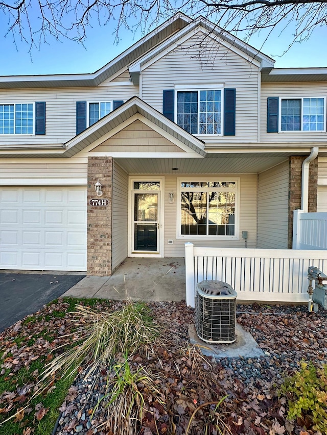 view of exterior entry featuring central air condition unit and a garage