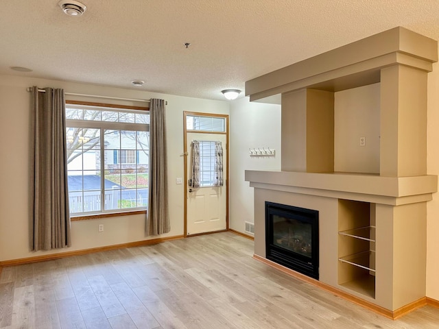 unfurnished living room featuring hardwood / wood-style floors and a textured ceiling