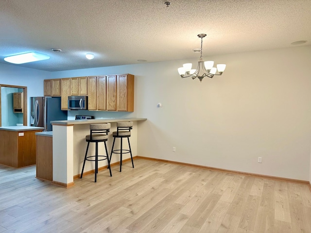 kitchen with decorative light fixtures, light hardwood / wood-style floors, and stainless steel appliances