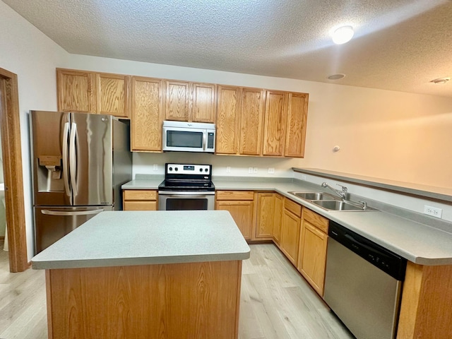 kitchen with appliances with stainless steel finishes, light wood-type flooring, a textured ceiling, and sink