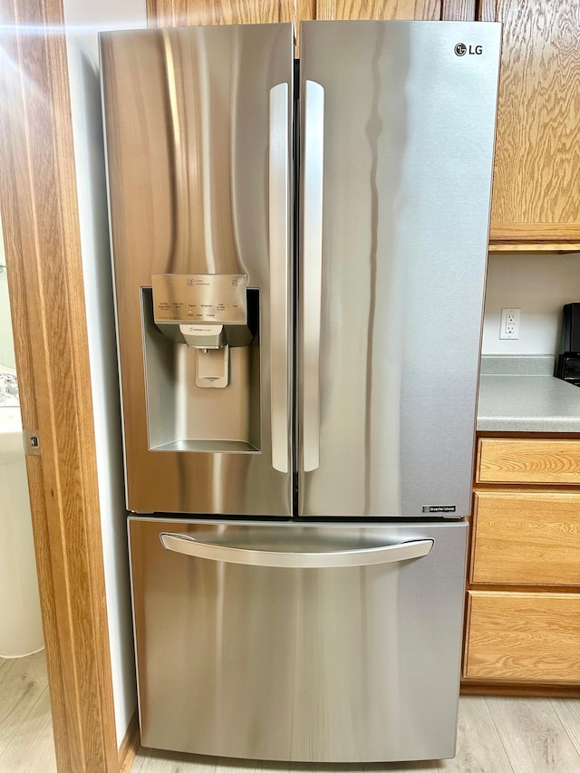 interior details with stainless steel refrigerator with ice dispenser, light hardwood / wood-style floors, and light brown cabinetry