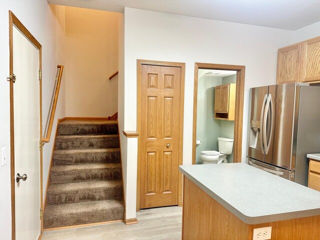 kitchen featuring light brown cabinets, stainless steel fridge with ice dispenser, a textured ceiling, and light hardwood / wood-style flooring