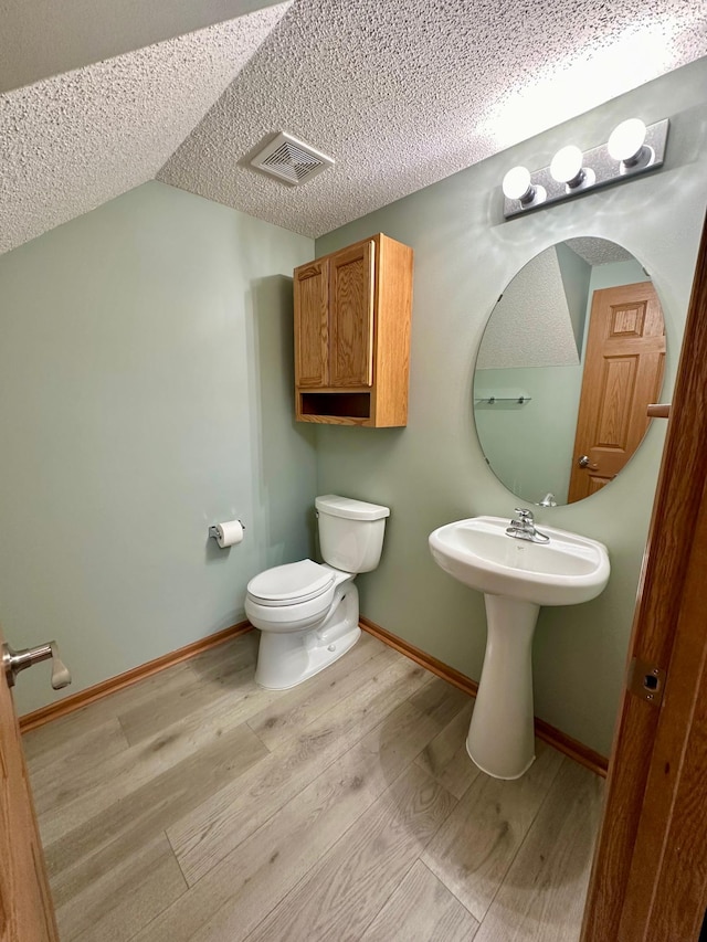 bathroom with hardwood / wood-style floors, a textured ceiling, and toilet