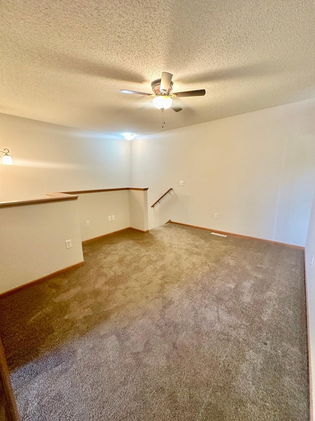 spare room featuring ceiling fan, carpet, and a textured ceiling