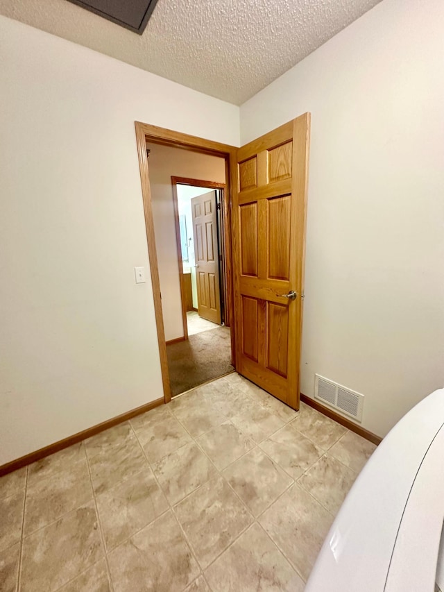 tiled empty room featuring a textured ceiling