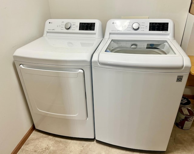 clothes washing area featuring light tile patterned floors and washing machine and clothes dryer