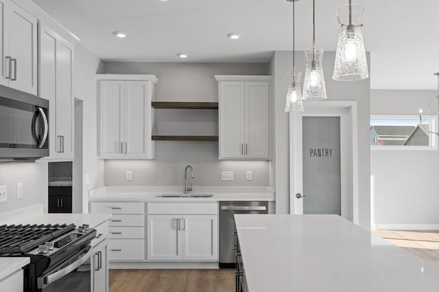 kitchen featuring white cabinetry, decorative light fixtures, and stainless steel appliances