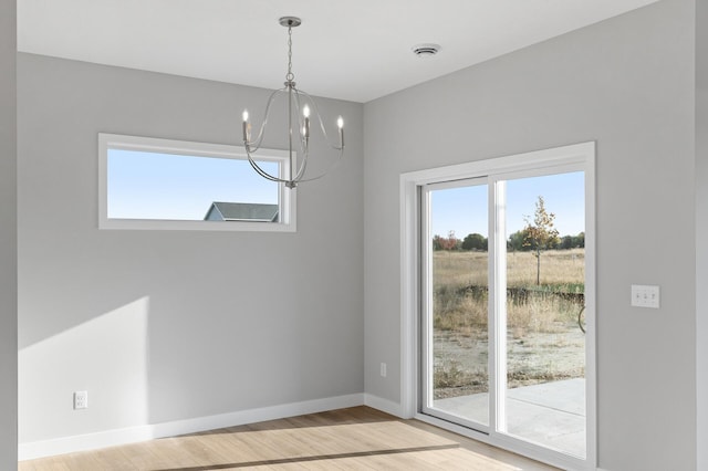 unfurnished dining area with light hardwood / wood-style flooring, a chandelier, and a wealth of natural light