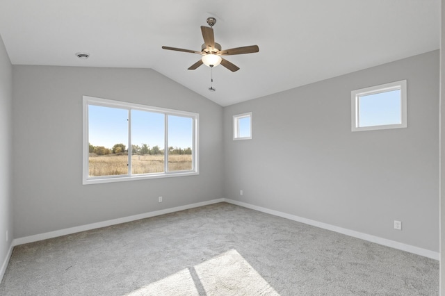 carpeted empty room with ceiling fan, a healthy amount of sunlight, and vaulted ceiling