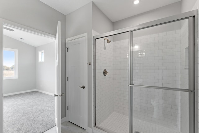 bathroom featuring a shower with door and vaulted ceiling