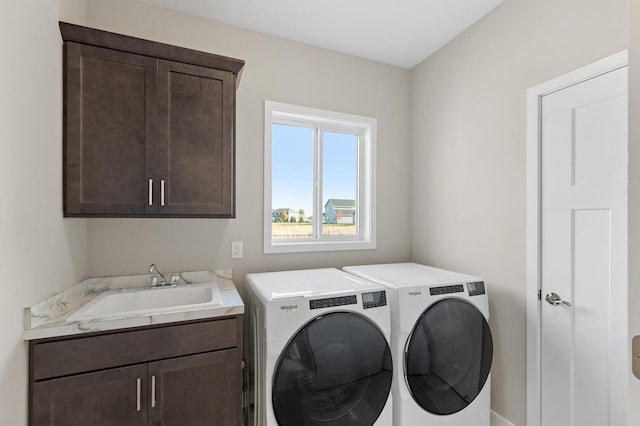 clothes washing area featuring cabinets, sink, and washer and clothes dryer