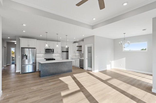 kitchen with a center island, decorative light fixtures, light wood-type flooring, white cabinetry, and appliances with stainless steel finishes