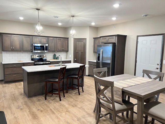 kitchen featuring appliances with stainless steel finishes, pendant lighting, dark brown cabinets, and sink