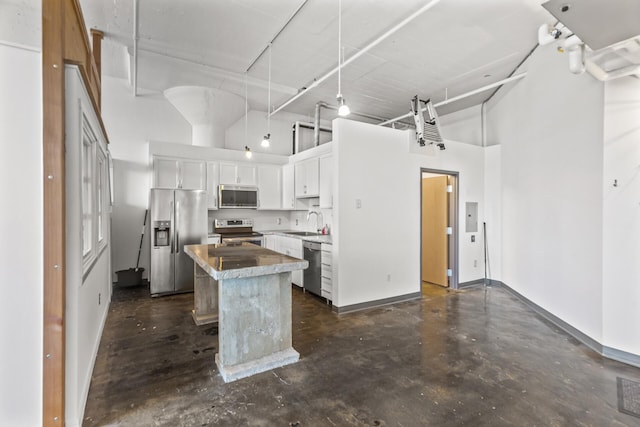 kitchen with appliances with stainless steel finishes, a towering ceiling, sink, white cabinets, and a center island