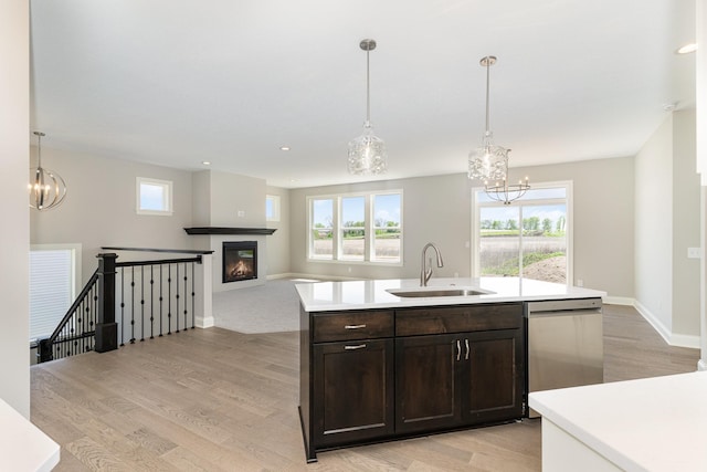 kitchen with sink, decorative light fixtures, stainless steel dishwasher, light wood-type flooring, and dark brown cabinets