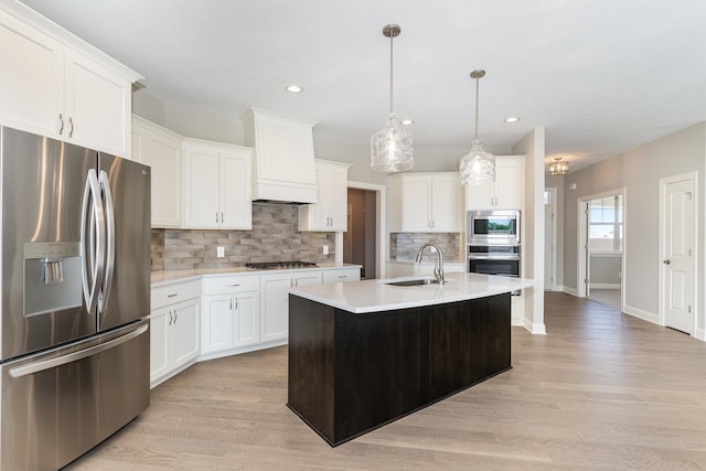 kitchen featuring sink, an island with sink, pendant lighting, white cabinets, and appliances with stainless steel finishes