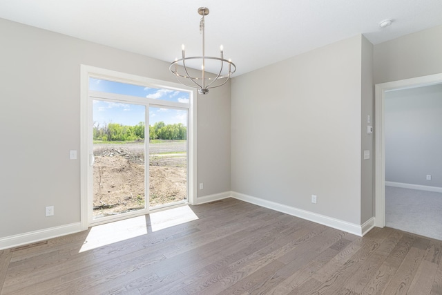 unfurnished dining area featuring hardwood / wood-style flooring and a chandelier