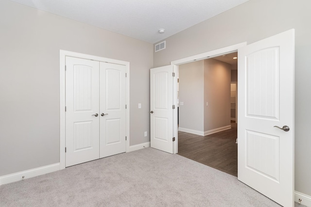 unfurnished bedroom featuring light carpet and a closet