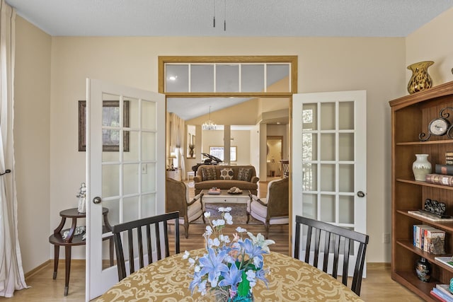 dining area with vaulted ceiling, a chandelier, french doors, and light hardwood / wood-style floors