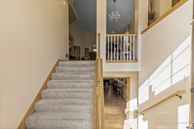 stairs featuring hardwood / wood-style floors, a notable chandelier, and a towering ceiling