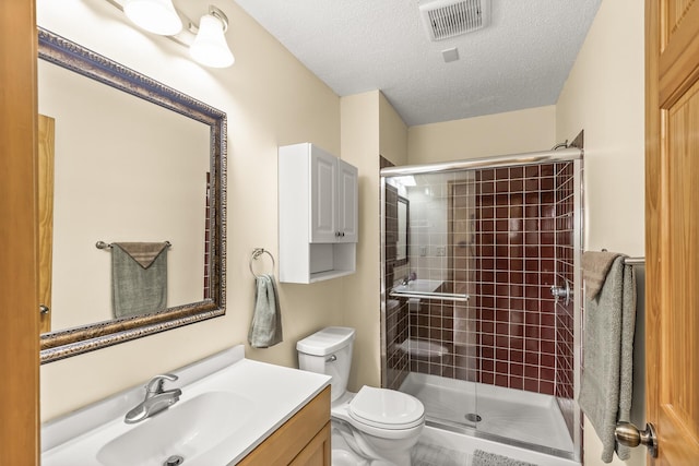 bathroom with vanity, a textured ceiling, toilet, and a shower with door