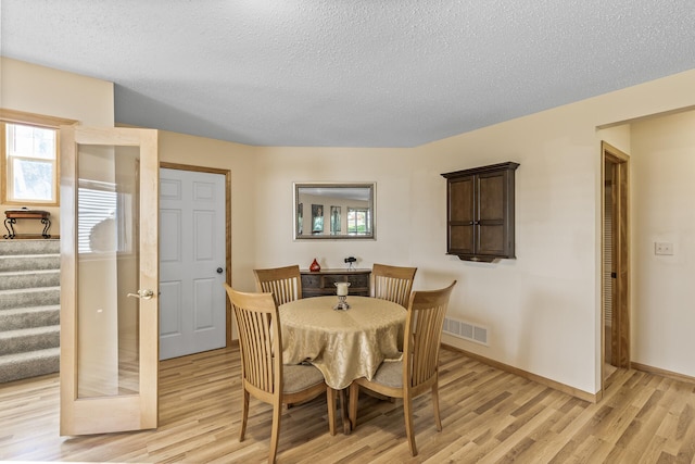 dining area with light hardwood / wood-style floors and a textured ceiling