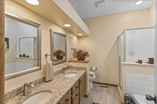 bathroom with vanity, walk in shower, toilet, and a textured ceiling