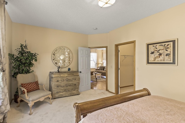 bedroom featuring a textured ceiling, carpet flooring, a closet, and a walk in closet