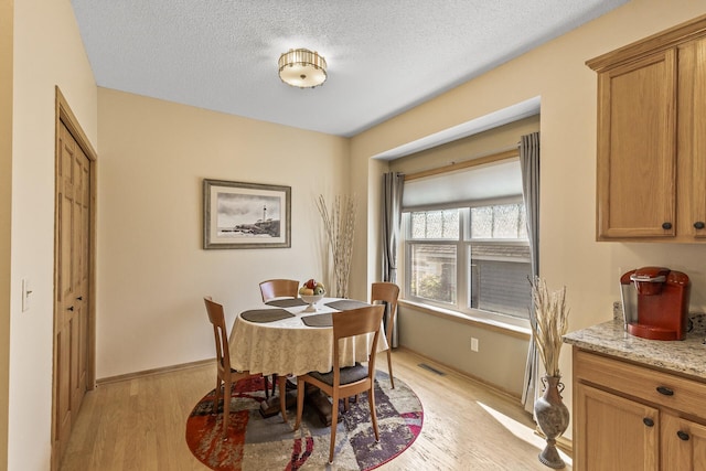 dining space featuring light hardwood / wood-style floors and a textured ceiling