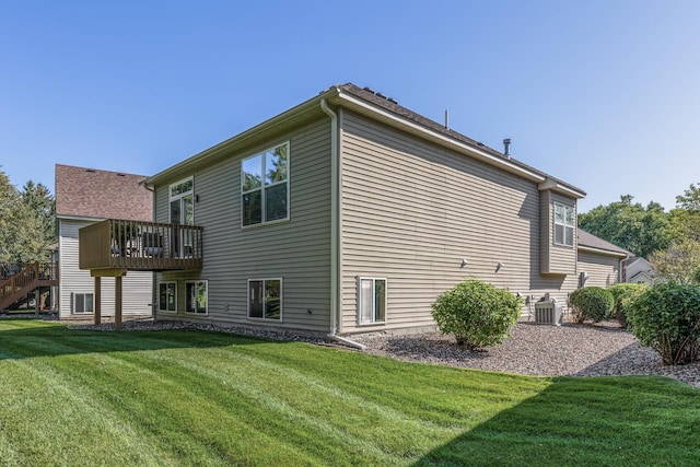 back of property featuring central air condition unit, a wooden deck, and a lawn