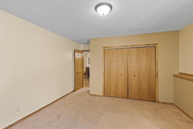 unfurnished bedroom with a closet, light colored carpet, and a textured ceiling