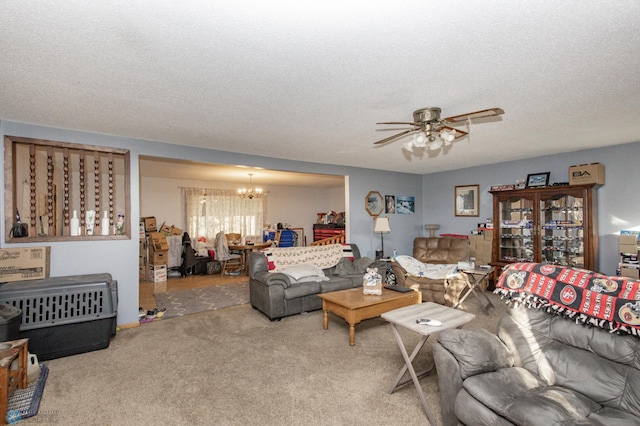 carpeted living room featuring a textured ceiling and ceiling fan with notable chandelier