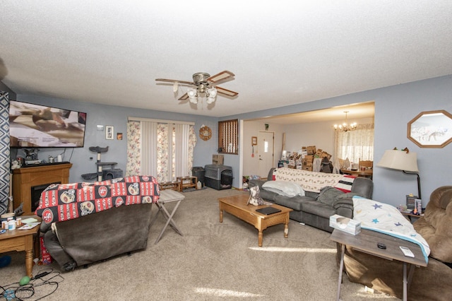 carpeted living room with a textured ceiling, ceiling fan with notable chandelier, and plenty of natural light