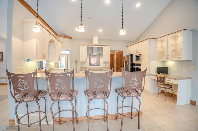 kitchen featuring wall chimney exhaust hood, a breakfast bar, stainless steel appliances, decorative light fixtures, and light tile patterned flooring