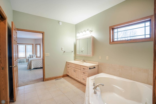 bathroom with tile patterned floors, tiled tub, and vanity